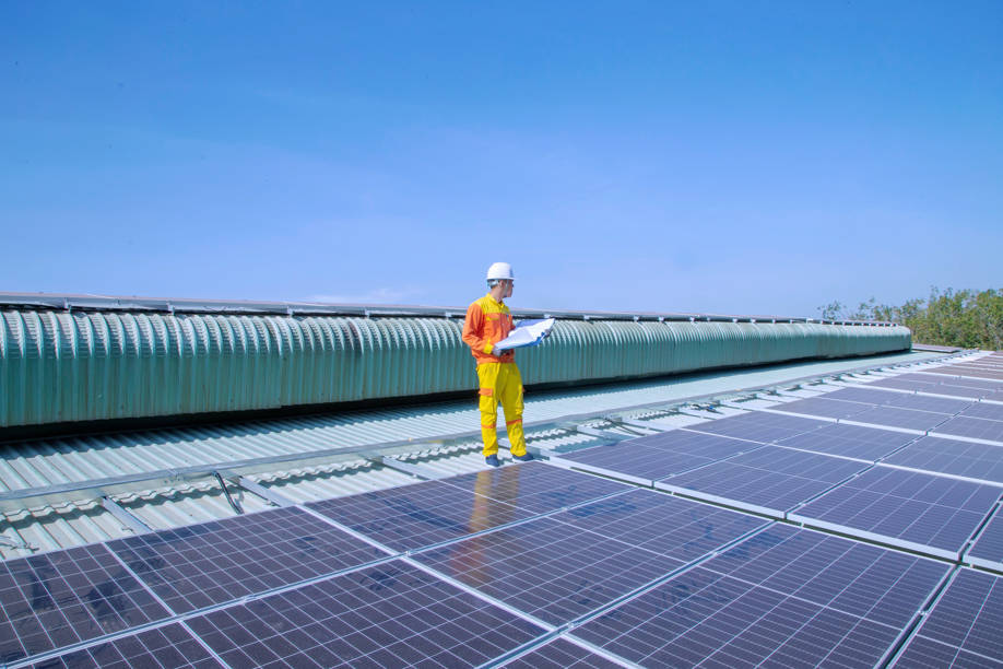 Arbeiter auf einem großen Solardach einer Gewerbeimmobilie